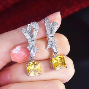 Close-up of bow earrings with radiant cut yellow stones and micro-pave crystals