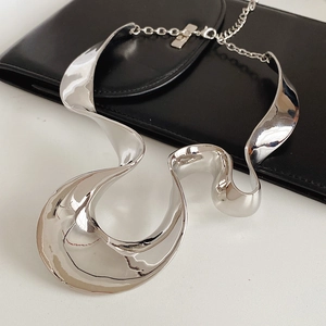 Close-up of polished silver geometric necklace on black leather and white background