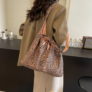 Large leopard print tote bag with wide shoulder strap and pink lining shown in a lifestyle setting