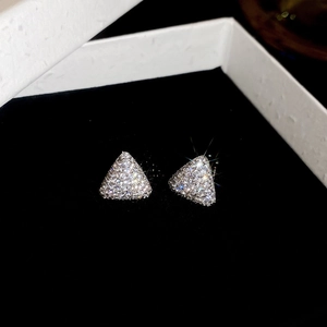 Vue macro de boucles d'oreilles triangulaires avec zircons sur fond de velours noir élégant