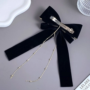 Detail of black velvet bow hair clip with gold bead tassel chains and metal spring clip