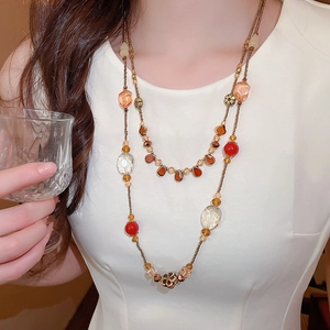 Long collier double rang avec perles en verre colorées et fleurs en métal sur mannequin