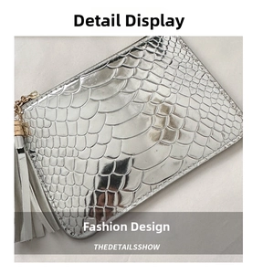 Detail of silver crocodile pattern clutch bag featuring fringe and metallic hardware