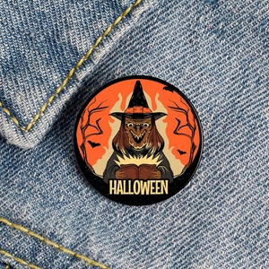 Halloween witch enamel pin with pumpkin and bat motif on blue denim fabric