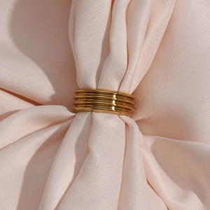 Polished 18K gold plated ribbed wide band ring on elegant beige silk fabric texture