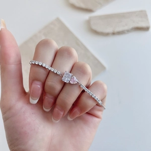 Detail of S925 silver tennis bracelet with pink heart and square zircon on a model wrist