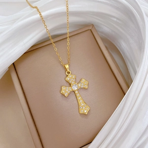 Detailed close-up of a gold cross necklace with crystal pavé on a jewelry box