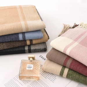 Classic plaid cashmere-like scarves in various colors with fringe on newspaper background