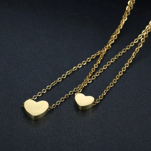 Macro detail of gold double heart pendants with a polished finish on a minimalist chain