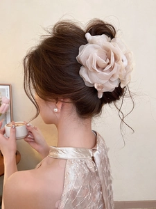 Detail of elegant champagne pink fabric rose hair claw clip on a low bun hairstyle