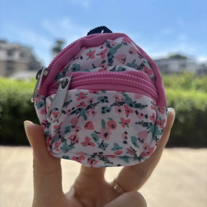 Close-up of floral canvas mini backpack keychain with pink zippers held in hand