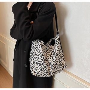 Detail of a large leopard print tote bag on a model shoulder with black straps
