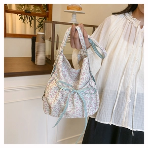 Detailed close-up of a floral canvas tote bag featuring a decorative pink ribbon bow accent