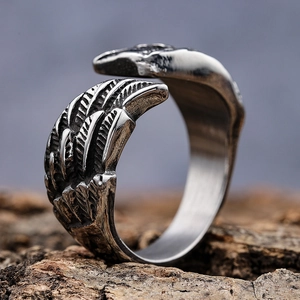 Vintage stainless steel open ring with detailed angel wing texture on rustic bark