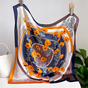 Elegant display of a silk-like square scarf with orange poppy flowers and geometric patterns