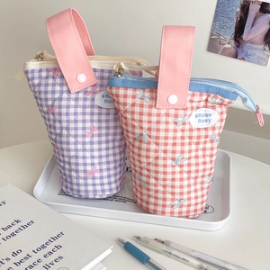 Detail of checkered quilted pencil cases with small bow patterns and snap hand straps
