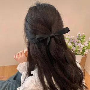 Detailed back view of a minimalist black satin ribbon bow hair clip on long hair