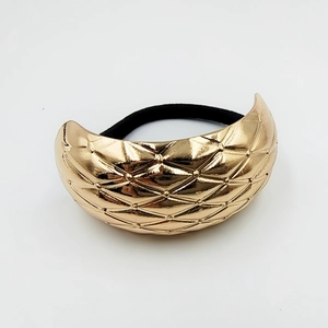Close-up of golden metal hair tie with classic diamond pattern and black elastic band