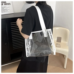 Transparent PVC tote bag with white canvas strap shown on shoulder in a modern setting