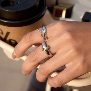 Minimalist multi-layer water wave ring and mixed metal band on model hand with coffee cup