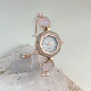 Detail of rose gold quartz watch with petal-shaped crystal bezel and floral bracelet links