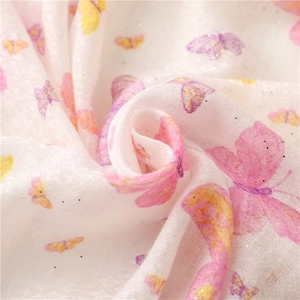 Detail of sheer white fabric with pink and yellow butterfly prints and silver glitter