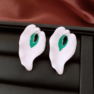 Close-up of irregular enamel flower earrings with green accents and white pearls