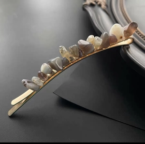 Natural crystal stone hair clip with vintage gold metal base on minimalist black stand