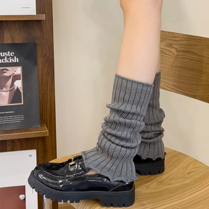 Close-up of gray knitted leg warmers styled with black patent leather loafers for JK style