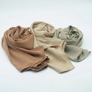 Detail of three satin chiffon scarves in earthy tones showing soft pleated texture