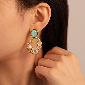 Baroque floral earrings with green gems and pearls on elegant model close-up