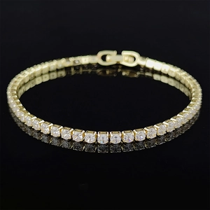 Close-up of golden tennis bracelet with round cubic zirconia on black reflective surface