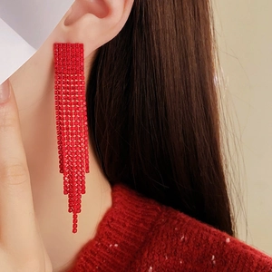 Detailed view of red fringe earrings with sparkling rhinestones worn on a model's ear