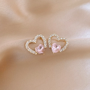 Close-up of heart-shaped gold earrings with pink gemstones and pavé zircon details