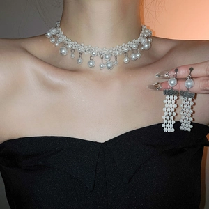Detail of vintage pearl necklace and tassel earrings set worn by a model