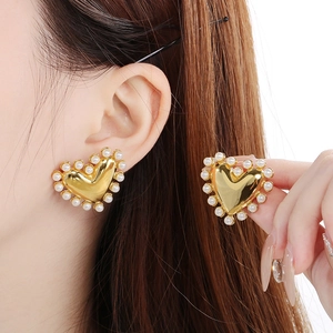 Detail of 18K gold plated heart earrings with pearl inlay worn by a model
