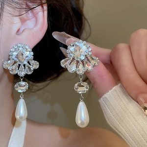 Detailed close-up of silver needle flower earrings with sparkling crystals and drop pearls