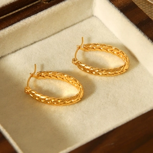 Detailed close-up of 18k gold plated stainless steel twisted C-shape hoop earrings on velvet