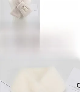 Detailed close-up of a soft beige faux fur scarf with an elegant fabric woven label