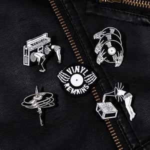 Close-up of retro black and white enamel pins on a black leather jacket texture