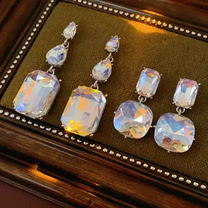 Elegant crystal drop earrings with teardrop and square tassels on vintage velvet display