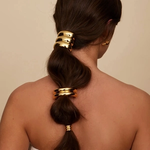 Detailed view of an 18k gold plated stainless steel half-round hair cuff on a ponytail