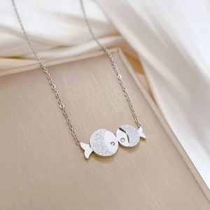 Close-up of silver kissing fish necklace with small diamonds on silk background