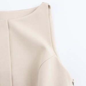 Detailed close-up of cream sleeveless dress with pleats and cotton linen texture