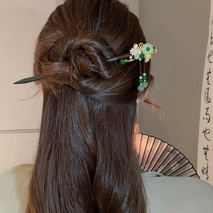 Detail view of Chinese butterfly hair pin with green beads and tassels in a hair bun