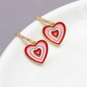 Detail view of gold heart earrings with red enamel layers and micro-pave cubic zirconia