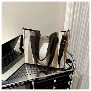 Detail of striped canvas tote bag with adjustable shoulder strap on a metal trolley