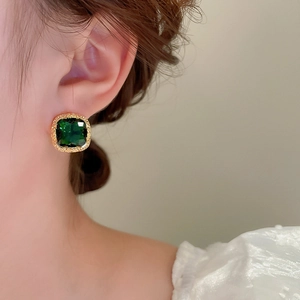 Close-up of square emerald zircon stud earrings with gold plating on a model