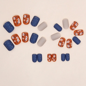 Short square matte press-on nails featuring orange floral and blue polka dot patterns