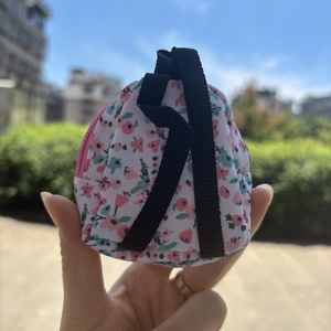 Detailed view of floral mini backpack coin purse held outdoors with a pink zipper